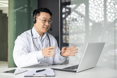 Physician in a lab coat talking on a laptop. Physician in a lab coat talking on a laptop.