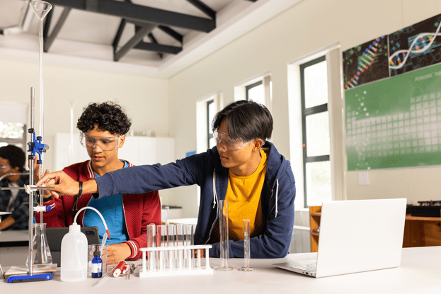Two high school students in a lab doing an experiment