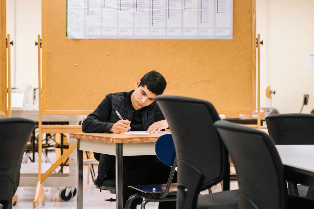 College student reviewing coursework at a classroom desk