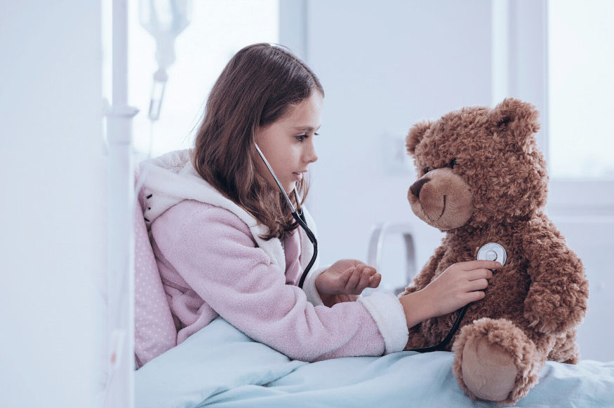 Young student using a stethoscope to listen to a teddy bear’s chest