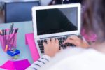 woman typing ona white laptop