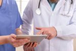 Doctor and nurse discussing patients tests at tablet computer in a hospital