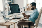 medical student sitting at his home desk, calculating the costs of medical school and related expenses