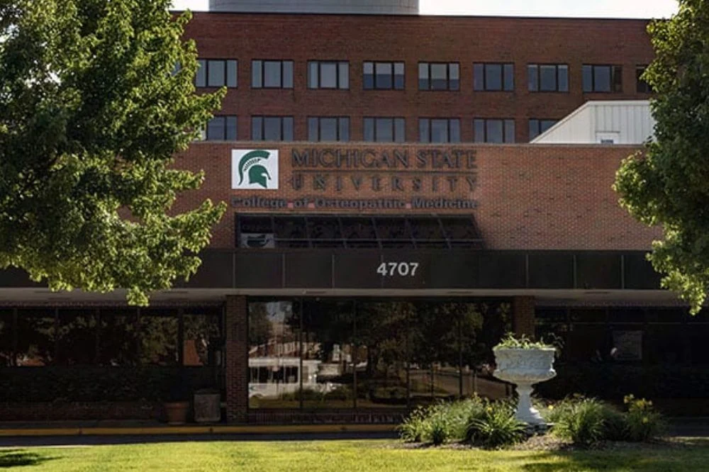 Front building view of the Michigan State University College of Human Medicine with the name of the school and school logo on the font of the building.