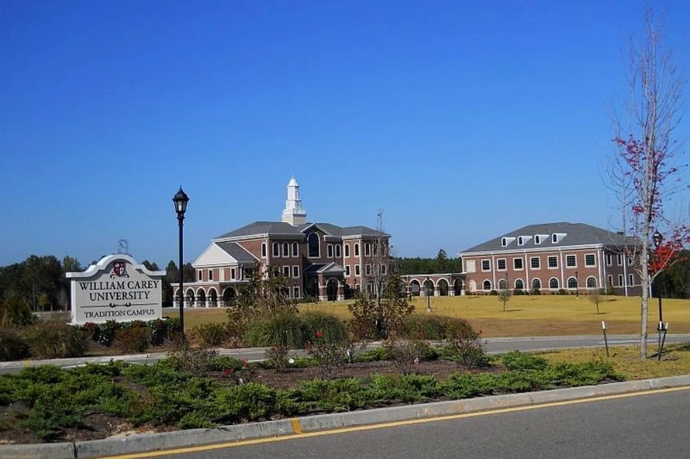 Front view of William Carey University College of Osteopathic Medicine School with sign in front of building