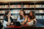 A group of the students sitting in a library in front of a computer.