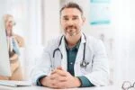 Doctor sitting at his desk in a white coat.