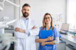 two medical professionals standing the a white coat and scrubs