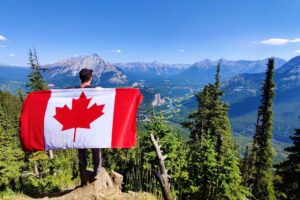 Medical Student holding a Canadian flag in the forest.