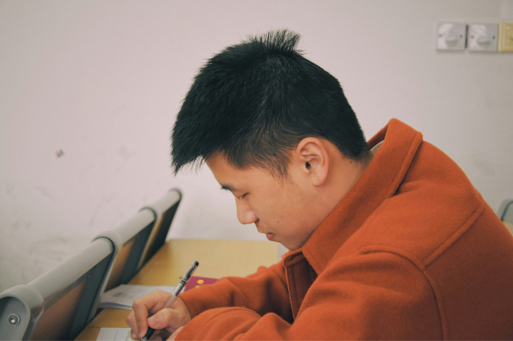 A medical student taking a test wearing an orange sweater.